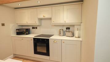 A kitchen with white cabinets, a black oven, a microwave, and a toaster.