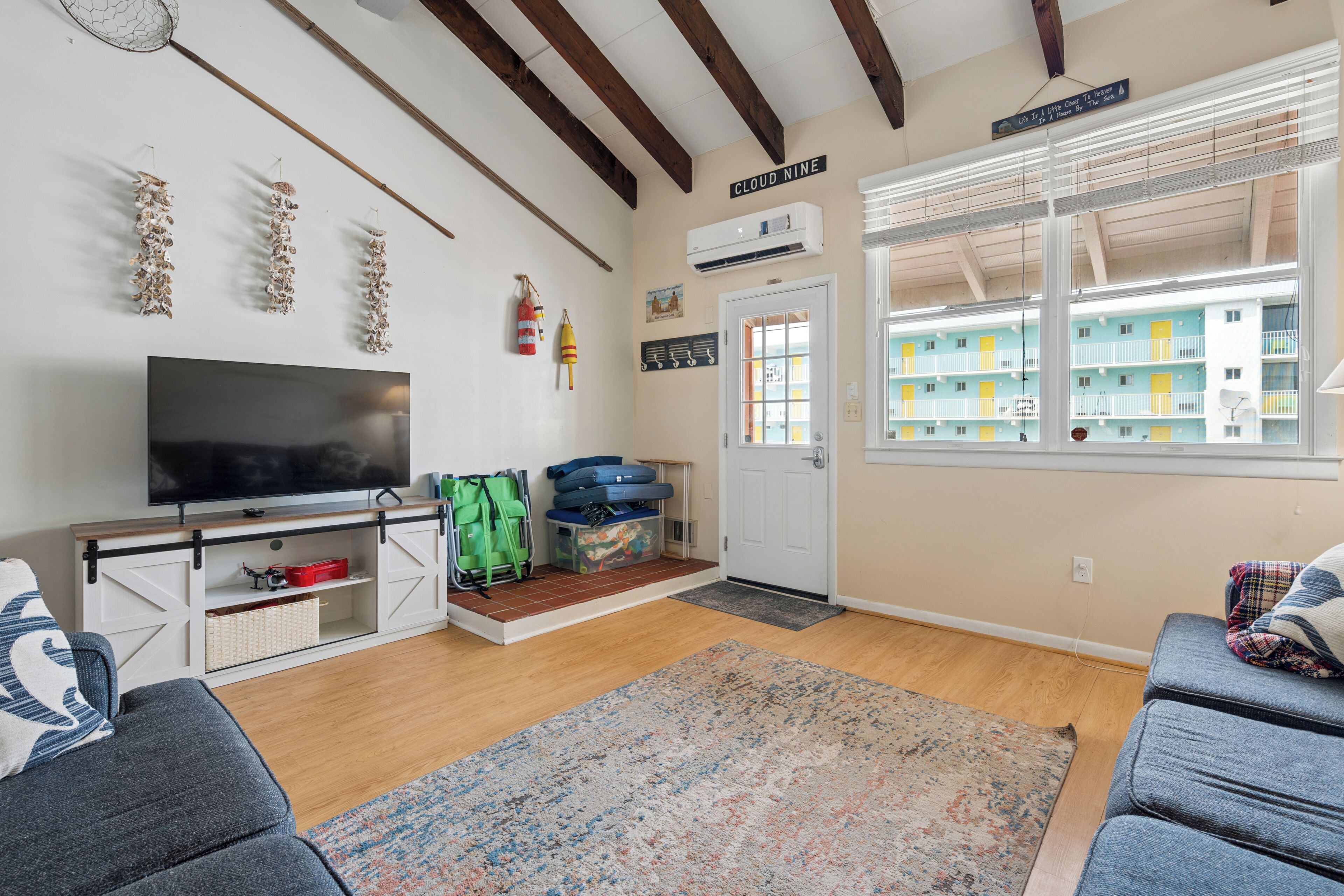 A living room with a television, sofas, a rug, and a view of a building outside.