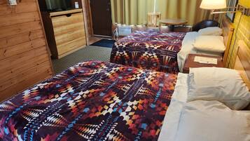 A hotel room with two beds, a television, a table, and a lamp.