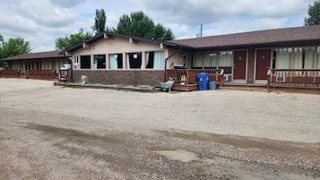 A motel with a gravel driveway, a wooden deck, and a stone facade.