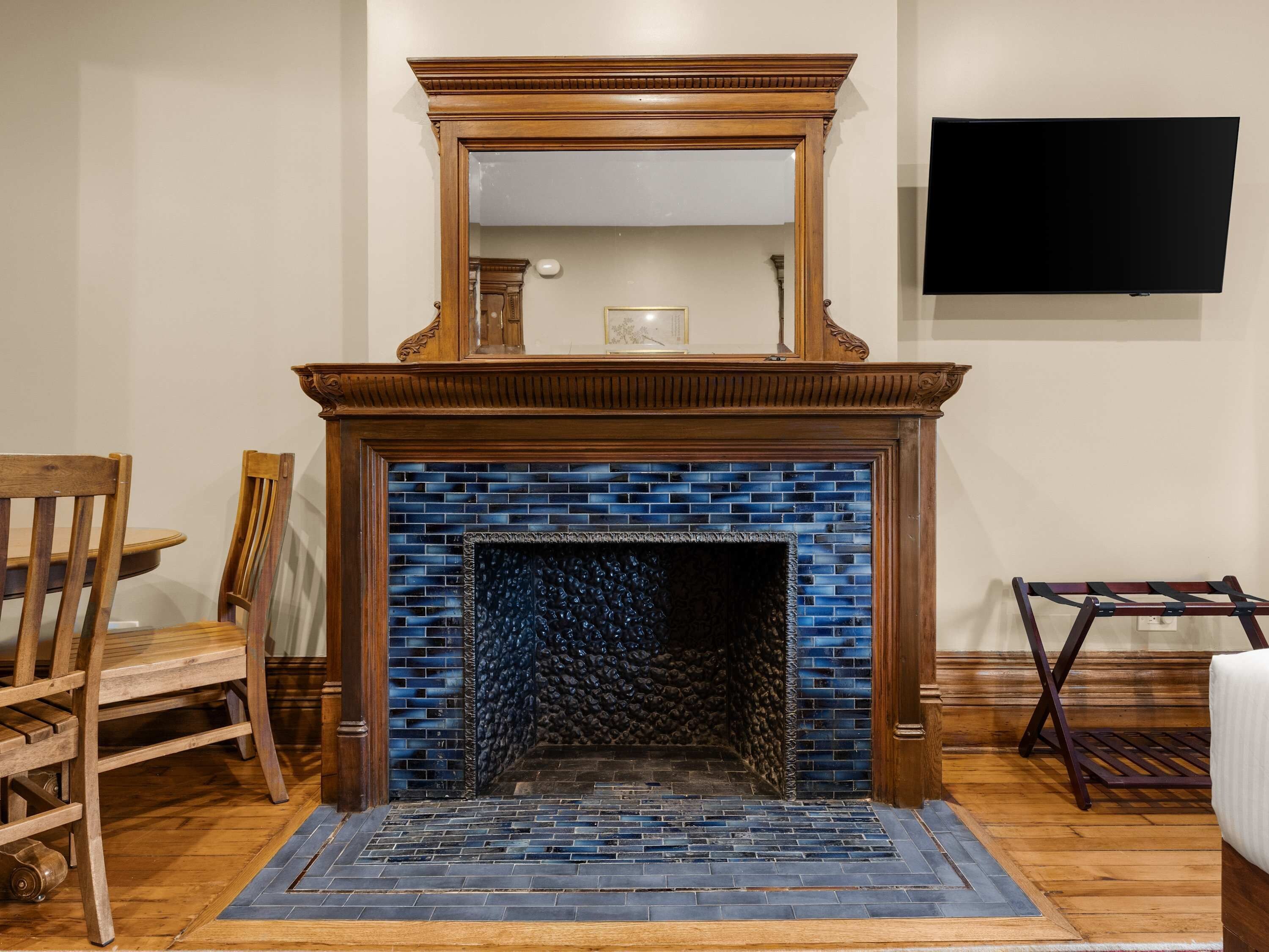 Una chimenea con un revestimiento de azulejos azules, un fuste de madera y un televisor de pantalla plana montado en la pared superior.