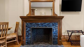 Una chimenea con un revestimiento de azulejos azules, un fuste de madera y un televisor de pantalla plana montado en la pared superior.
