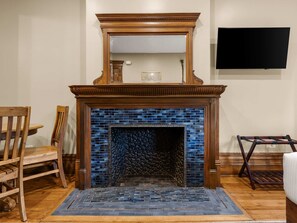 A fireplace with a blue-tiled surround, a wooden mantel, and a flat-screen TV mounted on the wall above it. - Hamilton House Studio Apt 4. Pvt Bath & Fireplace (Manhattan)