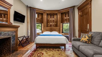Un dormitorio con una cama grande, un sofá, chimenea y paneles de madera.