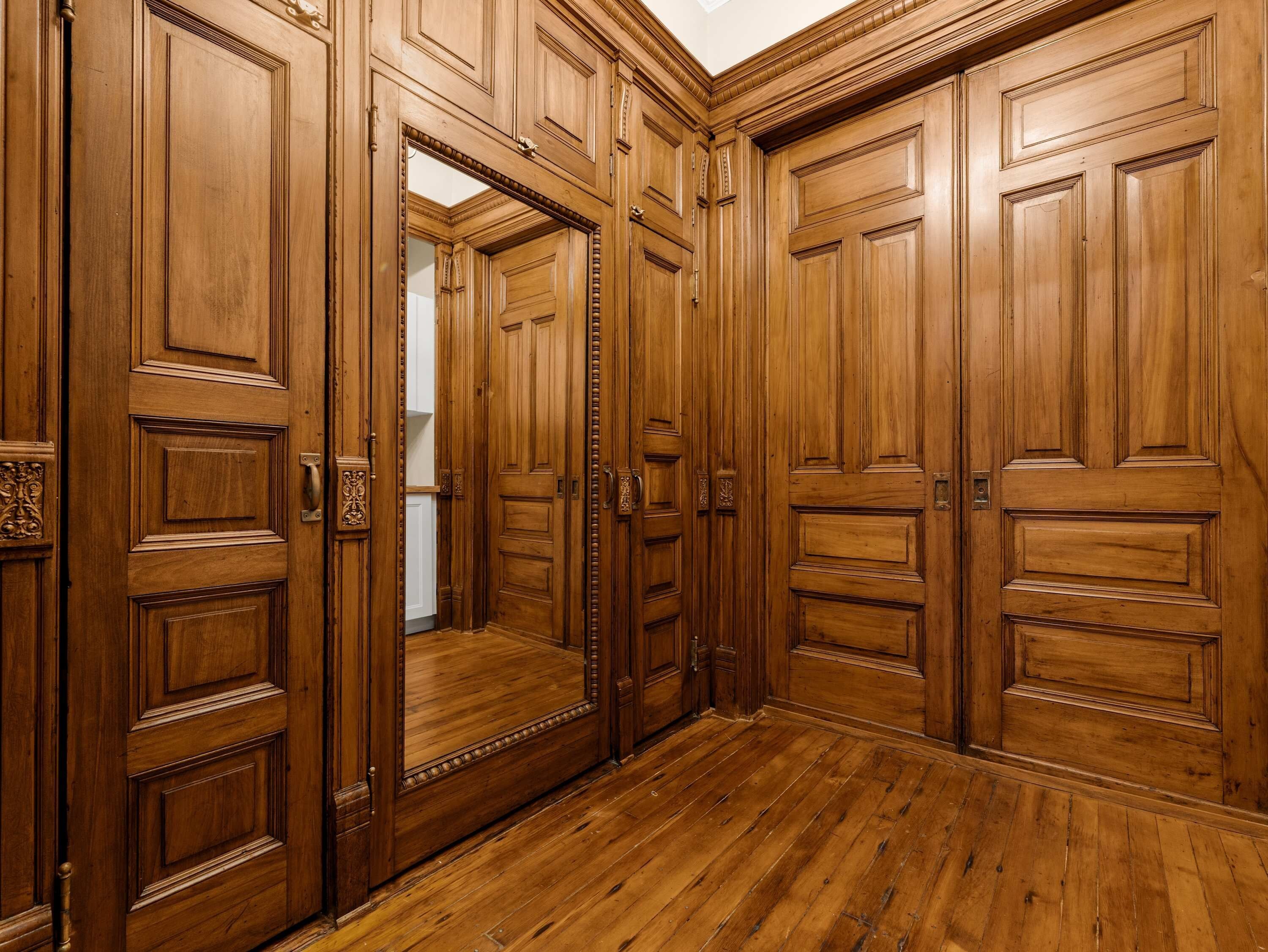 Un pasillo de madera con varias puertas y suelo de madera.