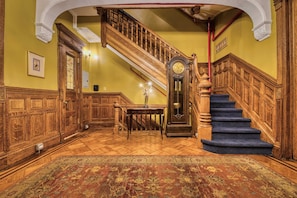 A grand staircase with a wooden handrail and blue carpeted steps, leading to an upper floor. - Hamilton House Studio Apt 4. Pvt Bath & Fireplace (Manhattan)