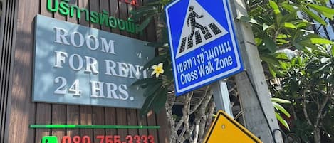 Placa de hotel com quarto para alugar, sinal de faixa de pedestres e um número de telefone.