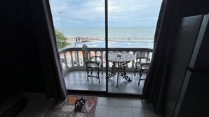 A balcony with a view of the beach, a table, and two chairs. - HiSSS Style (Cha-am)