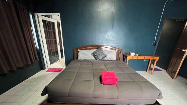 A standard hotel room with a bed, a wooden nightstand, a small table, and a door. - HiSSS Style (Cha-am)