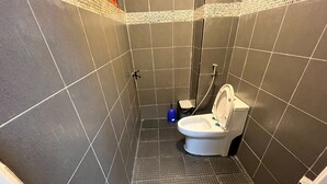 A small, enclosed bathroom with a toilet, a trash bin, and a blue cleaning brush. - HiSSS Style (Cha-am)