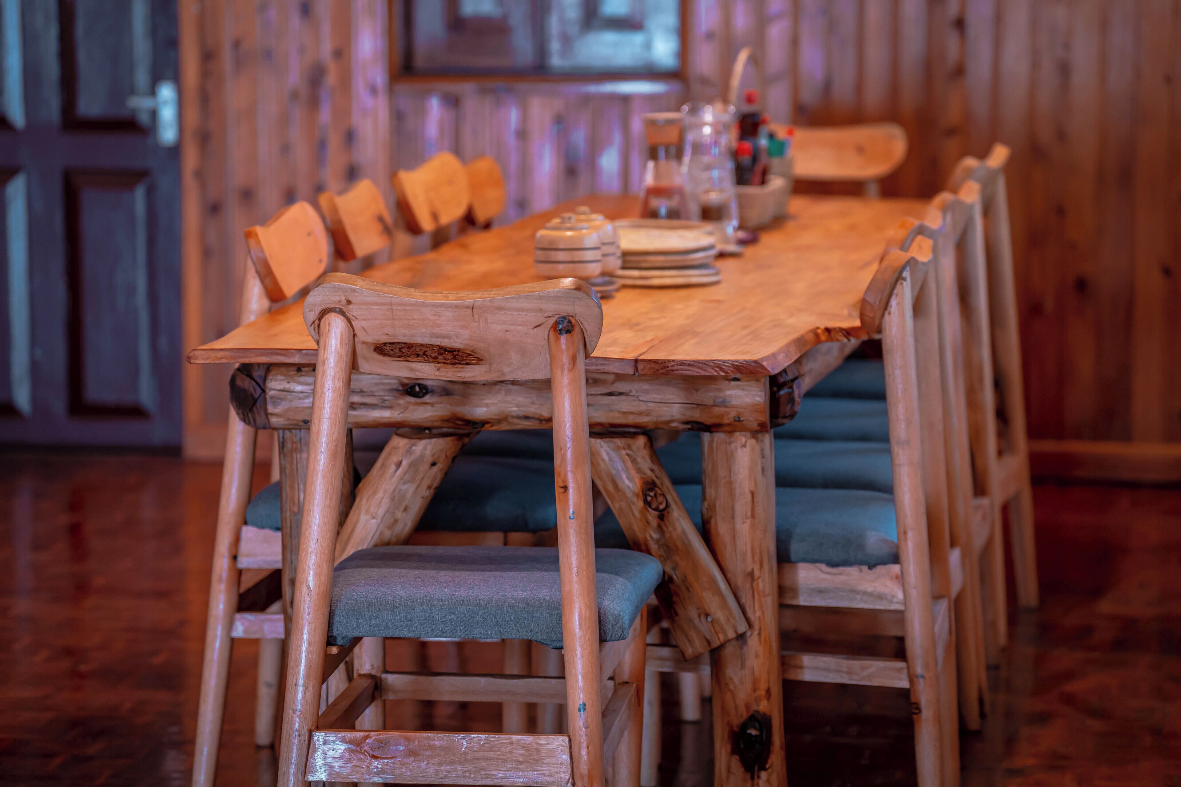 Una mesa de madera con sillas, un jarrón y una botella encima.
