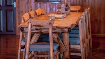 Una mesa de madera con sillas, un jarrón y una botella encima.