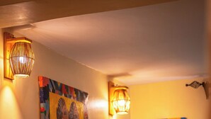 A room with a bed, a wall-mounted painting, and two wall sconces.