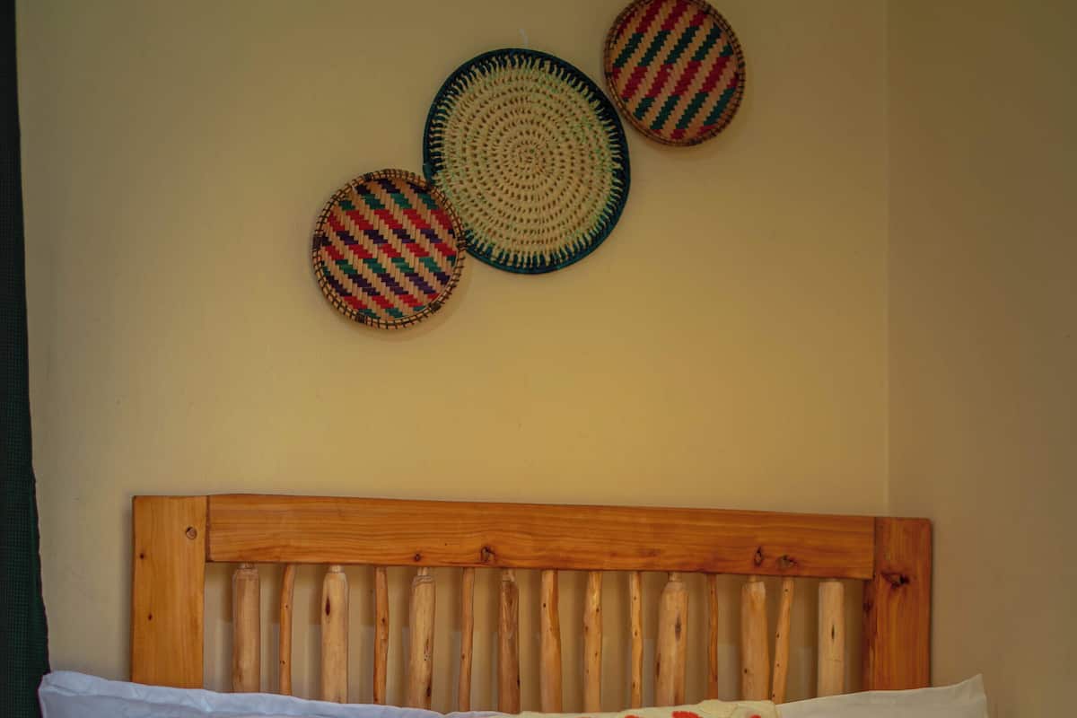 A bed with a wooden headboard, white and patterned pillows, and a brown blanket.