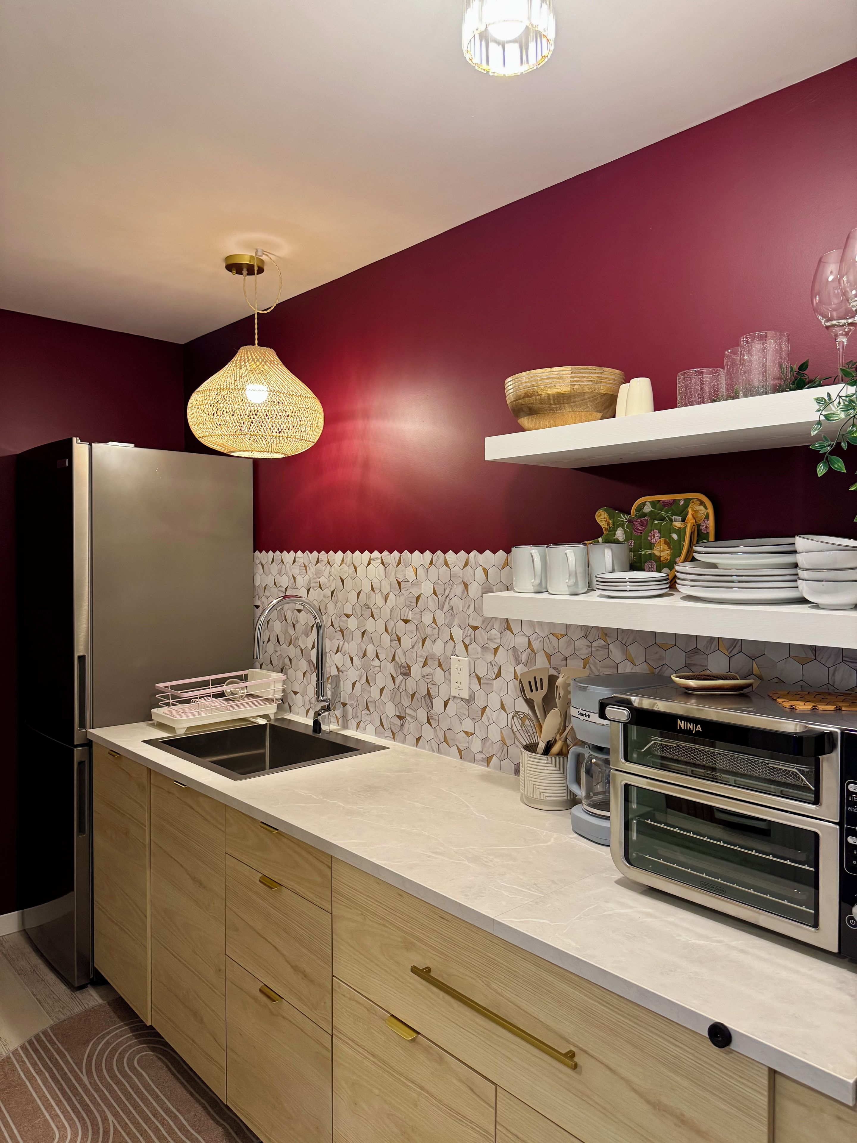 A modern kitchen with a stainless steel refrigerator, a built-in oven, and a hexagonal patterned backsplash.