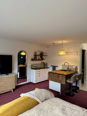 A compact hotel room with a bed, a TV, a kitchenette, and a seating area. - Les lofts de la rivière  (Matane)