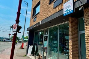 Um edifício de tijolos com uma fachada identificada como 'SPICERIE' e uma placa para 'Les lofts de la rivière', indicando um estabelecimento voltado para turistas.