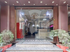 A hotel entrance with a glass door, a staircase leading inside, and potted plants on either side. - Suite Hotel Paras Inn (Amritsar)