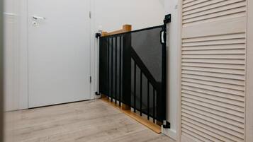 Un pasillo con una puerta blanca, un cercado de seguridad negro y suelo de madera.