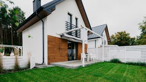 Una casa moderna con fachada blanca, puerta principal de madera y un porche cubierto.