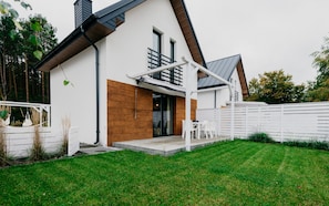 Una casa moderna con fachada blanca, puerta principal de madera y un porche cubierto.