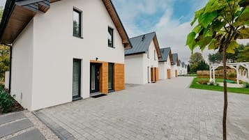 A row of modern houses with a paved walkway, wooden accents, and a clear sky.