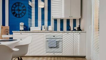Una cocina moderna con armarios blancos, horno empotrado y un reloj en la pared.