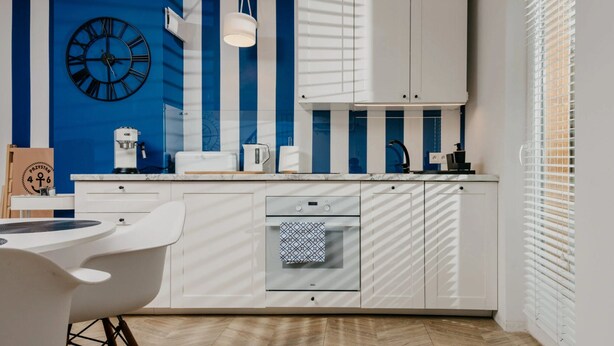 Una cocina moderna con armarios blancos, un reloj y una cafetera.