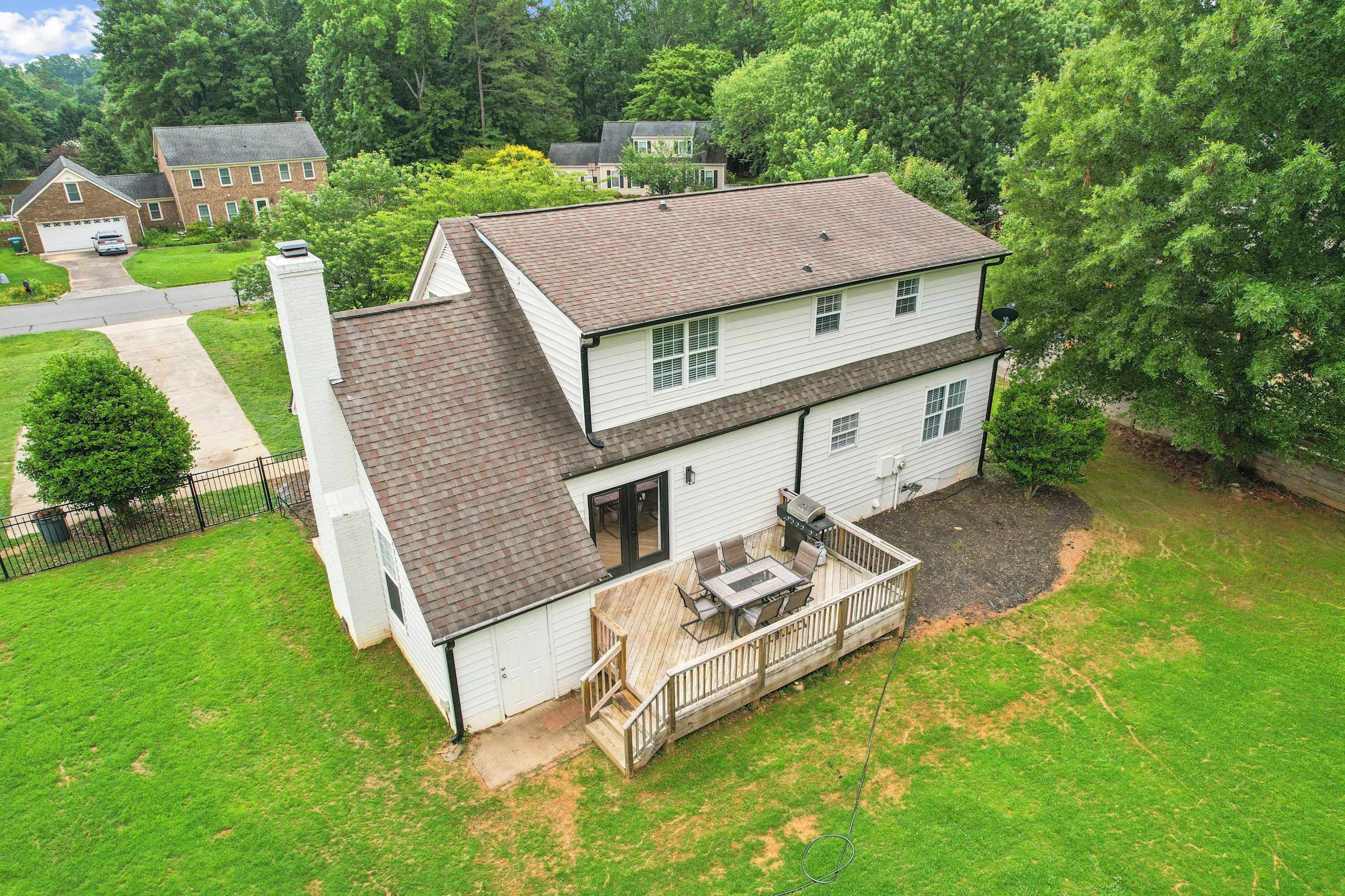 A two-story house with a deck, a garage, and a well-maintained lawn.