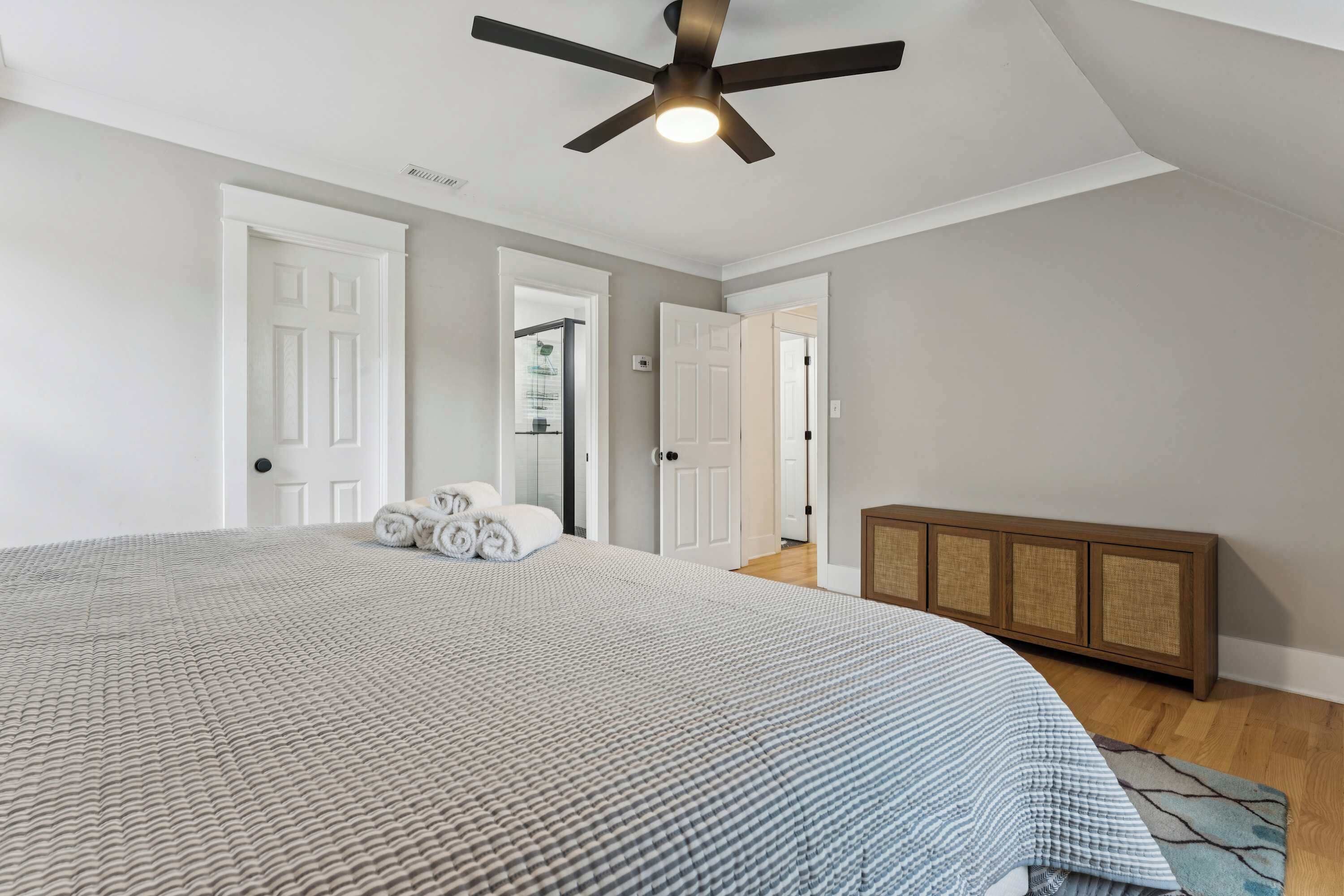 Une chambre à coucher avec un grand lit, un ventilateur de plafond et une armoire en bois.