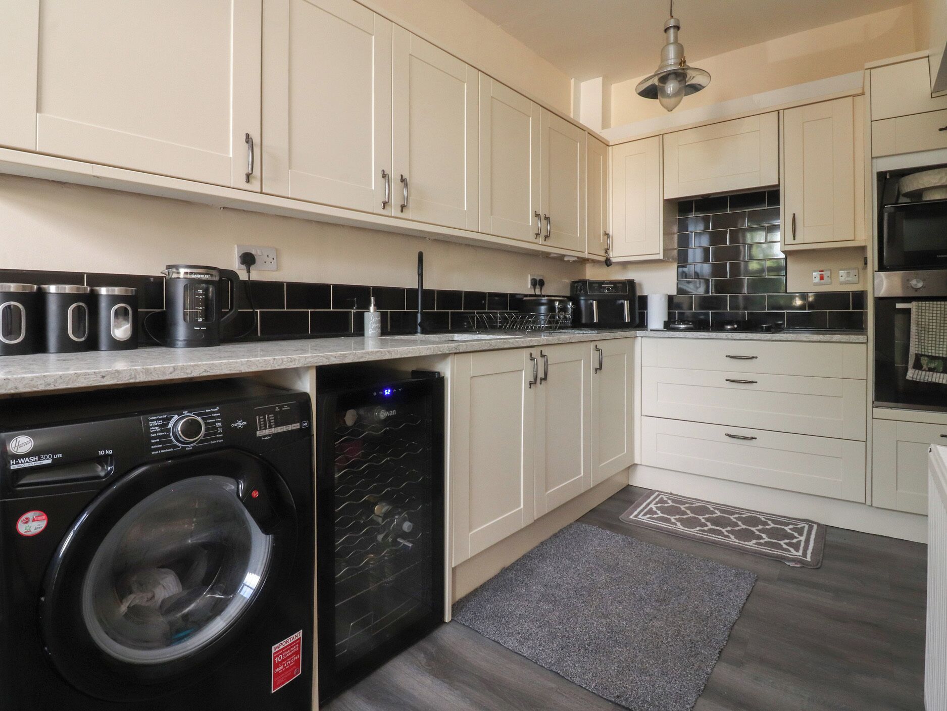 A modern kitchen with a washing machine, a coffee maker, and a microwave.