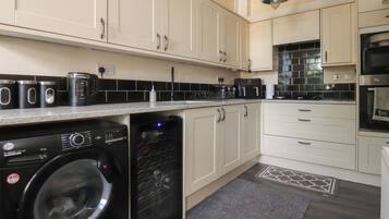 A modern kitchen with a washing machine, a coffee maker, and a microwave.