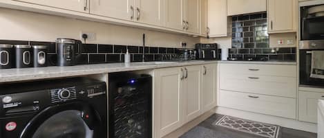 A modern kitchen with a washing machine, a coffee maker, and a microwave.