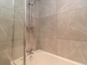 Ein Badezimmer mit Duschkabine, Badewanne und Marmorfliesen.