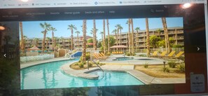 Een resort met een zwembad, palmbomen en een gebouw met balkons.