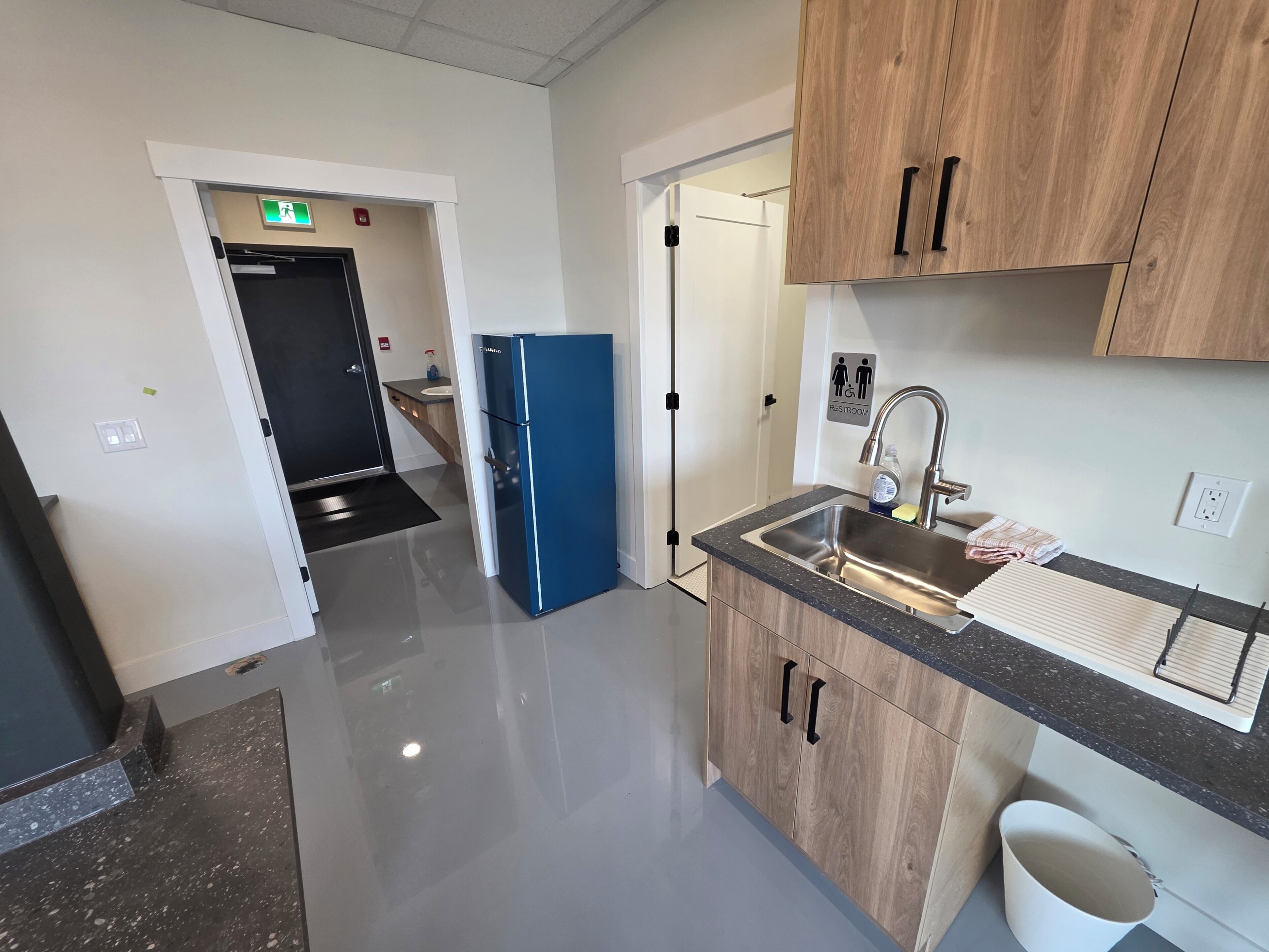 Een moderne keuken met een spoelbak, kasten en een blauwe koelkast.