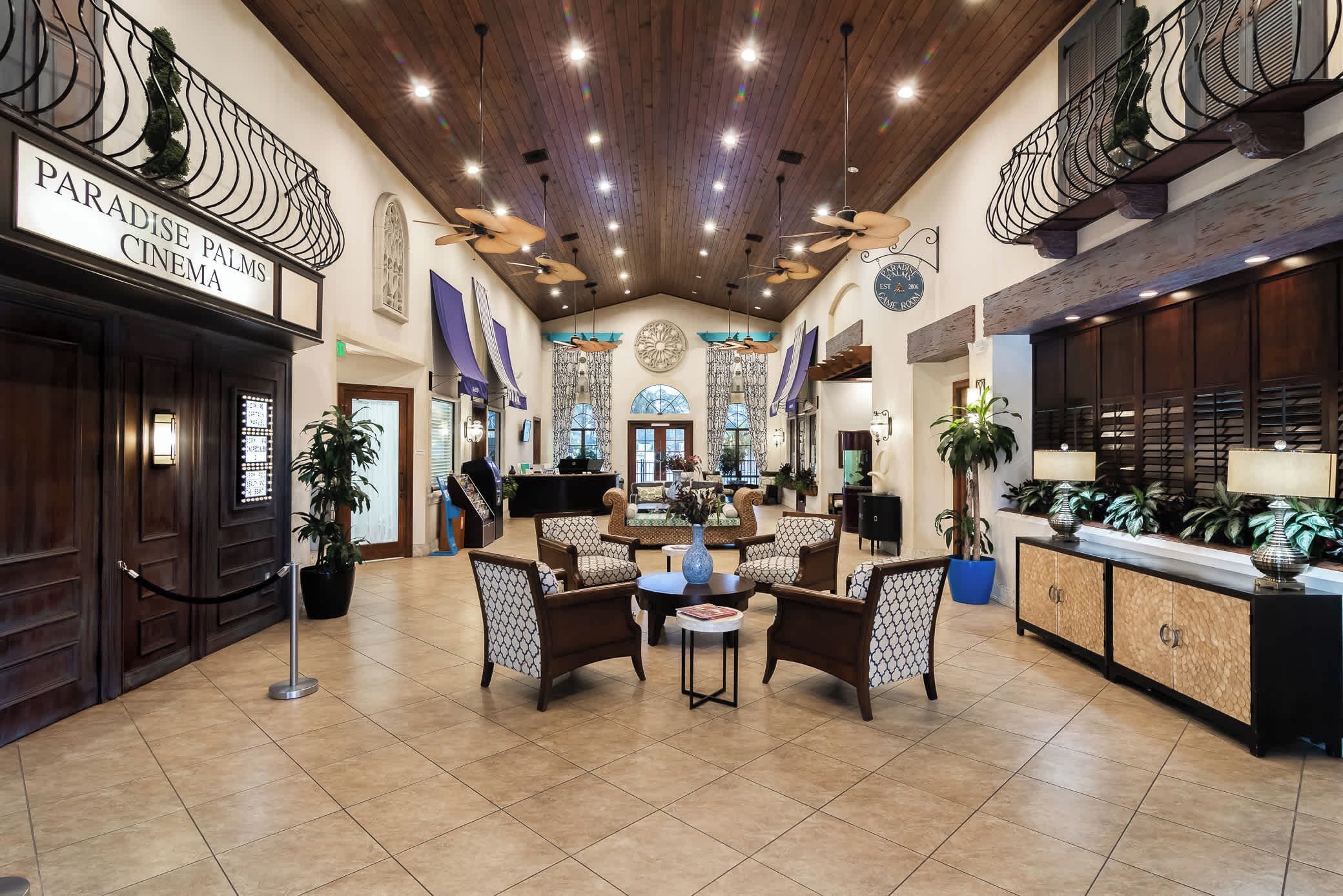 Un hall d’entrée avec un comptoir de réception, un espace détente et un panneau indiquant le cinéma Paradise Palms.