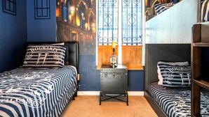 A dormitory room with two beds, a nightstand, and a mural of a cityscape. - Golden Hours at Paradise Palms (Kissimmee)