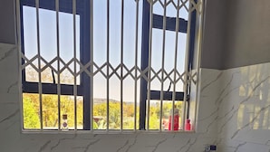Un baño con inodoro, lavamanos y ventana con vistas a árboles.
