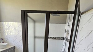 Un baño moderno con cabina de ducha, tocador con lavamanos y suelo de baldosas.