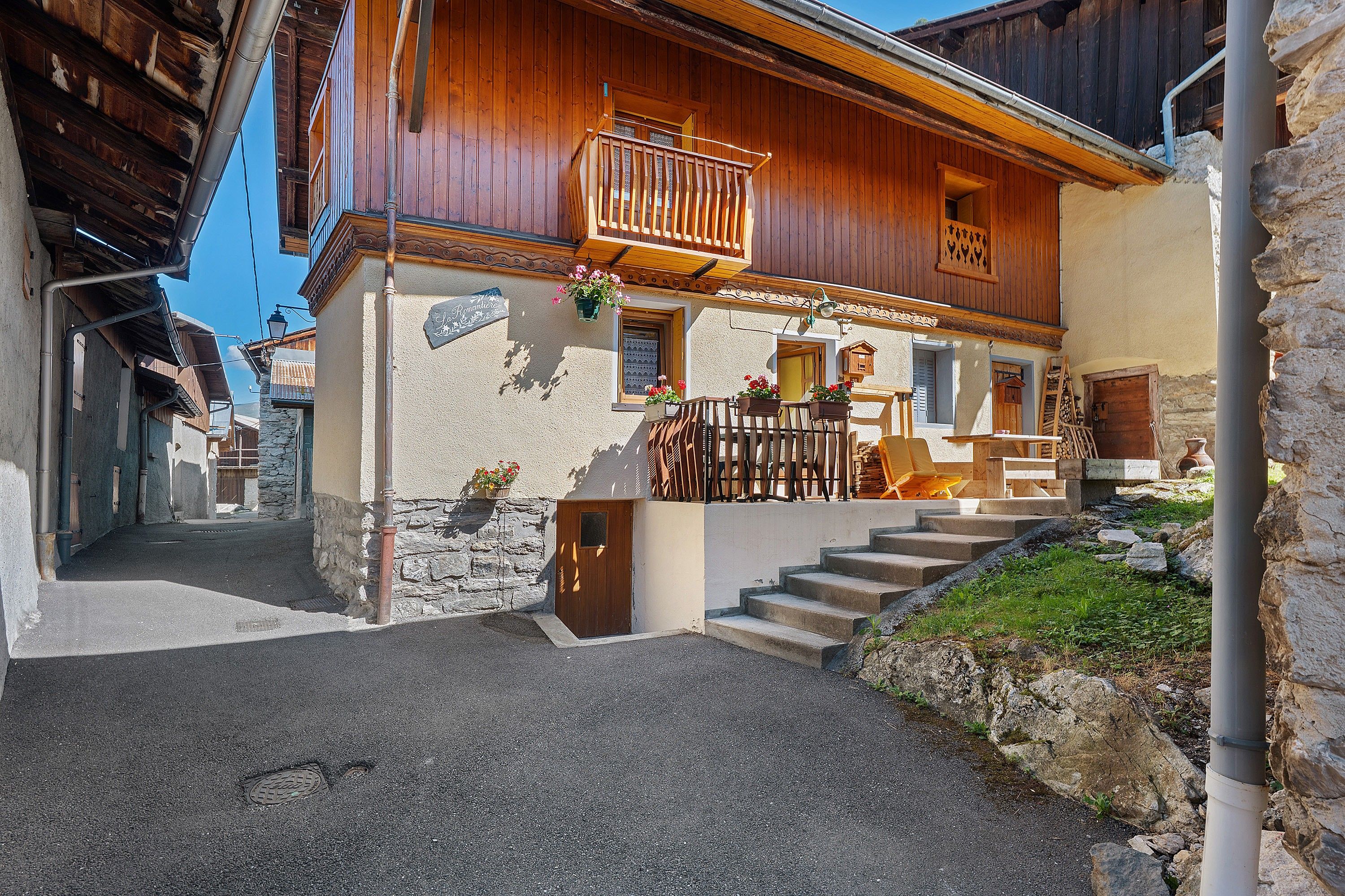 A traditional wooden building with a balcony, stone steps, and a sign indicating a restaurant.