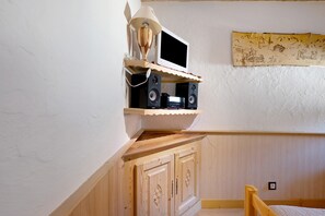 Een kamer met een houten kast, een wandtelevisie en een muur met een decoratief wandtapijt.