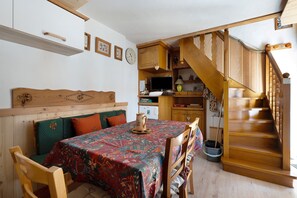 Ein gemütliches Zimmer mit einer hölzernen Bank, einem Tisch mit gemustertem Tischlein und einer Treppe mit Holzhandläufen.
