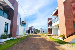 Una zona residencial moderna con edificios de ladrillo y blanco, un camino de grava y plantas pequeñas.