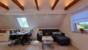 Una stanza in stile loft con angolo pranzo, un divano a divano nero, un tavolino e una finestra vista.