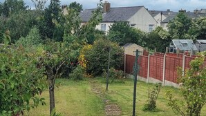 A garden with a path, various plants, and a red fence. - Ehen Cottage (Cleator Moor)