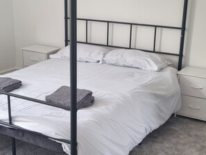 A single bed with a metal frame, white bedding, and two nightstands with drawers.