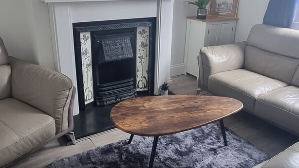 A living room with a fireplace, leather sofas, a coffee table, and a rug. - Ehen Cottage (Cleator Moor)
