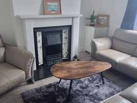 Una sala de estar con chimenea, sofás de cuero, una mesa de centro y una alfombra.