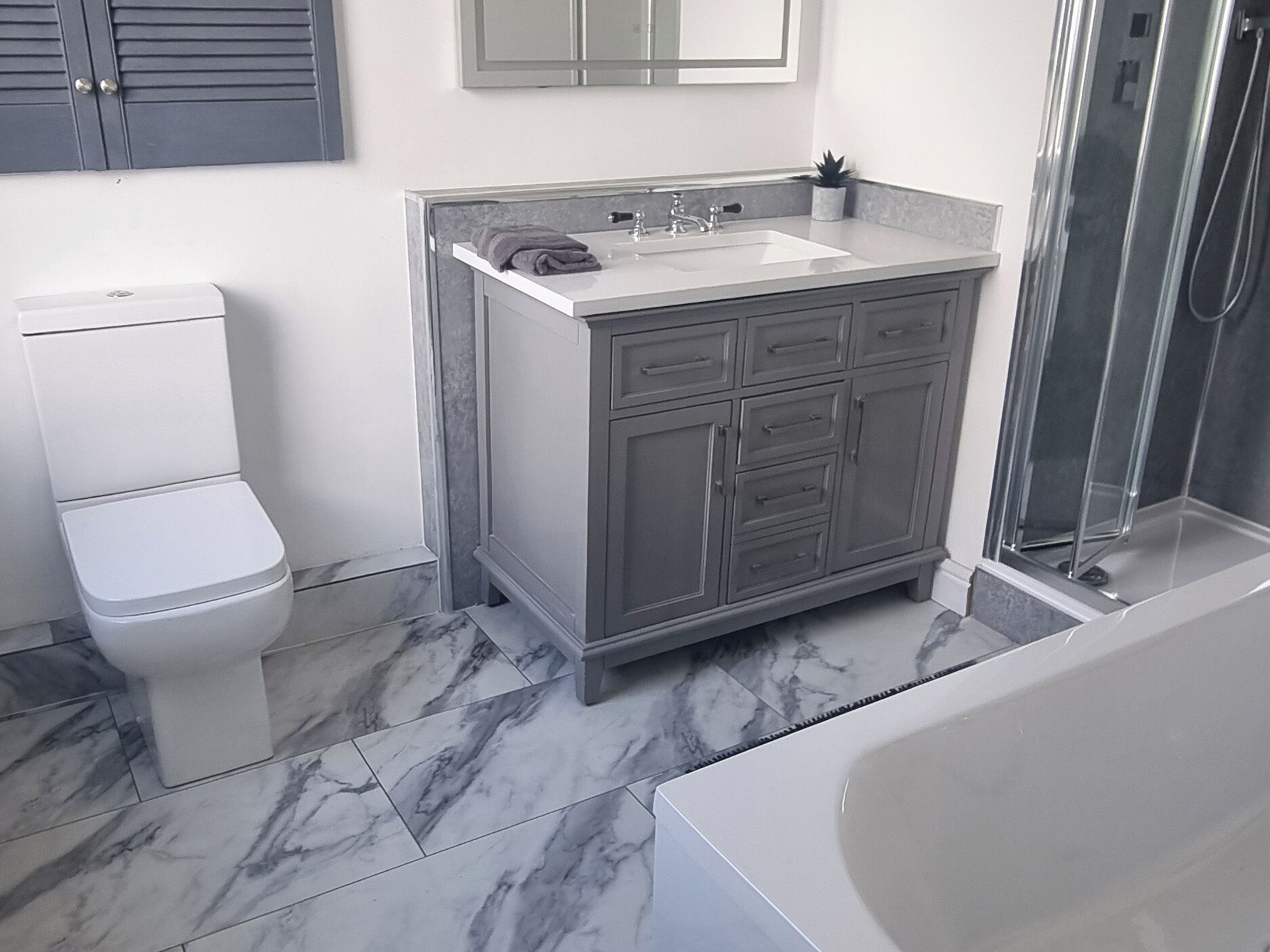 A bathroom with a toilet, a sink with a mirror above, and a shower area.